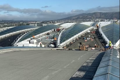 Crew installing structural steel and skylight framing across a large facility roof